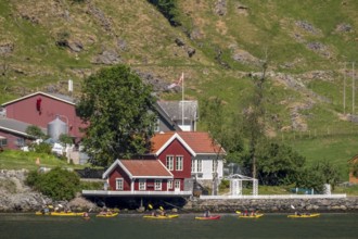 Tourists in yellow kayaks on fjord, river, Gudvangen, stone wall, mountain landscape, red wooden