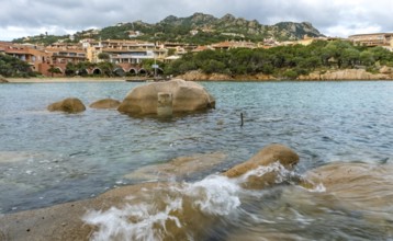 Sardinia, waves on the rocky coast, residential complex in the picturesque harbour town of Porto