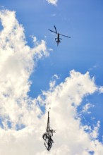 Helicopter lifts tree in cloudy sky, transport helicopter, timber transport, Saas Grund, Canton