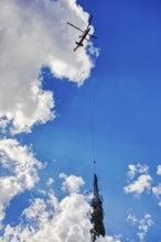Helicopter transports tree under cloudy sky, transport helicopter, timber transport, Saas Grund,