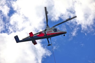 Helicopter moving in the cloudy sky, transport helicopter, timber transport, Saas Grund, Canton