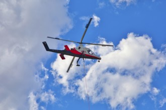 Helicopter hovering in the sky with white clouds, transport helicopter, timber transport, Saas