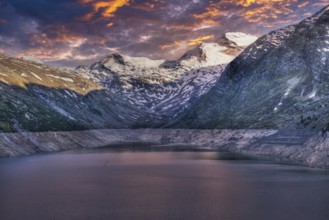Snowy mountain peaks and a lake at sunset with pink and purple sky, Mattmark reservoir, Saas