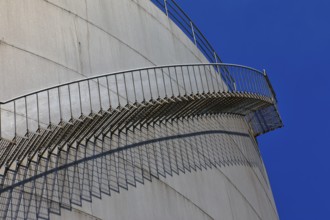 Metal staircase winds around a large tank in an industrial environment, elevated tank, chemical,