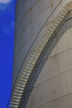 Metal staircase on a large industrial gas tank under a clear blue sky, elevated tank, chemical,