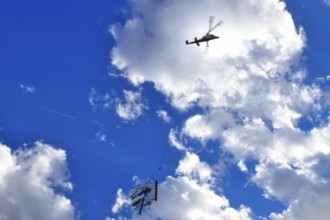A helicopter transports a tree under a sunny, cloudy sky, transport helicopter, timber transport,