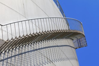 The staircase runs along a large tank in front of a clear blue sky, high tank, chemical, company,
