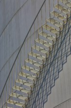 Close-up view of a metal staircase on an industrial gas tank with long shadow lines, elevated tank,