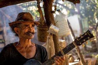 Sugar cane farmer in Valle de los Ingenios plays guitar for the tourists, Trinidad, Cuba, Sancti
