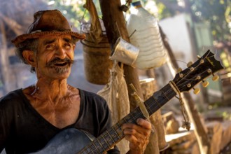Sugar cane farmer in Valle de los Ingenios plays guitar for the tourists, Trinidad, Cuba, Sancti
