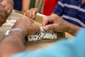 Old Cubans playing dominoes at a table on the street in the city centre of Trinidad, Trinidad,
