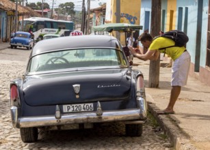 Tourist taking pictures in a vintage car at the roadside in the old town of Trinidad, Trinidad,