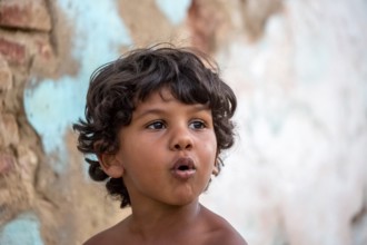 Little Cuban boy on the street in front of an old wall, Street scene in the old town of Trinidad,