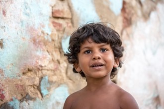 Little Cuban boy on the street in front of an old wall, Street scene in the old town of Trinidad,