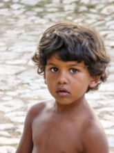 Little Cuban boy on the street in front of an old wall, street scene in the old town of Trinidad,