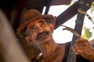 Sugar cane farmer in Valle de los Ingenios plays guitar for the tourists, Trinidad, Cuba, Sancti