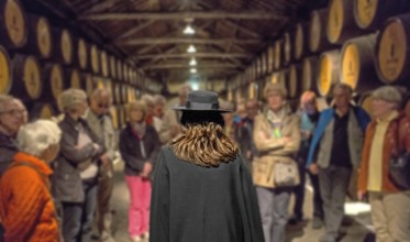 Group of visitors with traditional travel guide, port wine barrels, wine cellar of the Sandemann