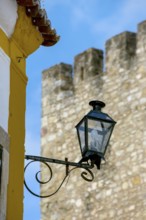 Picturesque small town Obidos, street lamp in front of city wall, Ãbidos, district Leiria,