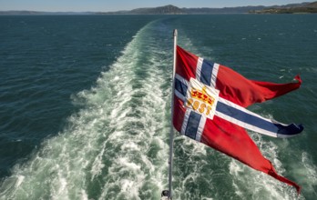 The post symbol on Norwegian flag of a Hurtigruten ship, foaming spray, Trondheimfjord, Agdenes,