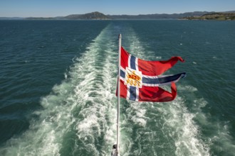 The post symbol on Norwegian flag of a Hurtigruten ship, foaming spray, Trondheimfjord, Agdenes,