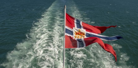 The post symbol on Norwegian flag of a Hurtigruten ship, foaming spray, Trondheimfjord, Agdenes,
