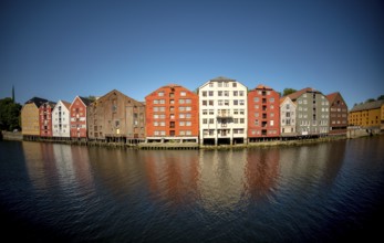 Warehouse city, picturesque colourful houses and commercial buildings on the river Nidelva, pile