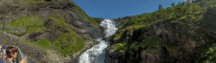 Kjosfossen waterfall, tourist looking at waterfall near Fureberget, rock faces, trees, sky, Flåm,
