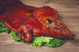 Baked, fried piglet, on a wooden table, no people, The whole piglet is baked and served on the