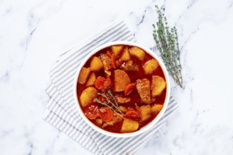 Meat goulash with potatoes and carrots, sweet peppers, in a saucepan, top view, traditional