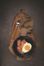 Fried egg with bacon, in a cast-iron pan, breakfast, top view, close-up, homemade, no people