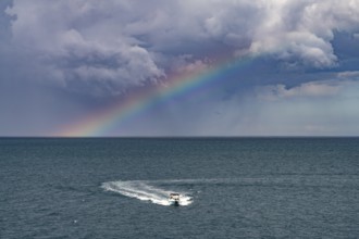 Rainbow over the Adriatic Sea and motorboat near Polignano a Mare, Apulia, Italy
