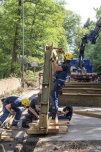 Construction of a temporary bridge over a slipped road crossing a stream, by the bridge