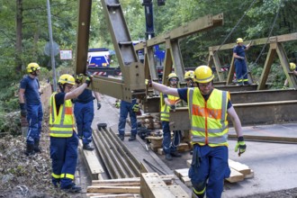 Construction of a temporary bridge over a slipped road crossing a stream, by the bridge