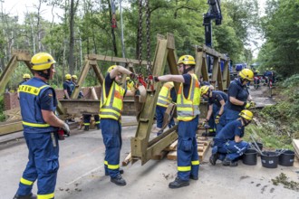 Construction of a temporary bridge over a slipped road crossing a stream, by the bridge