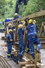 Construction of a temporary bridge over a slipped road crossing a stream, by the bridge