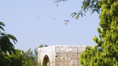 Türkiye special operations police hang from a helicopter with ropes, carrying weapons and unfurling