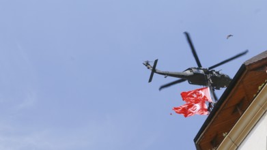 Türkiye special operations police hang from a helicopter with ropes, carrying weapons and unfurling
