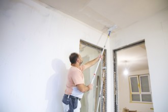 Wallpapering work: Priming the ceiling for the application of wallpaper