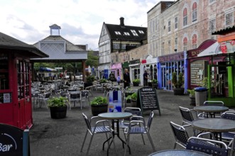 Colourful shops and empty tables at a busy market under a cloudy sky, London, England, United