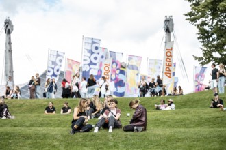 Visitors relaxing in a meadow at the Superbloom Festival, Day 1 in the Olympic Park, Munich,