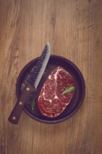 Steak made from fresh beef, with herbs and various spices, in a clay pan, with a kitchen knife,