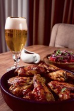 Delicious barbecue chicken wings, with French fries, salad and a refreshing drink, at a cozy table,