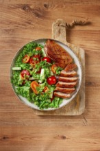 Delicious grilled duck breast served with fresh garden salad and cherry tomatoes at a rustic dining