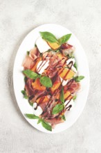 Salad with prosciutto and melon, with arugula and cheese, with balsamic sauce, natural light