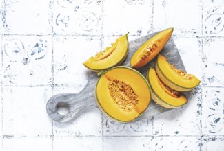 Freshly sliced melon slices, cantaloupe melon, on a wooden chopping board, close-up