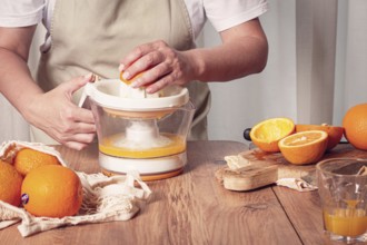 Preparation of freshly squeezed orange juice, using a juicer, in a cozy kitchen setting