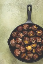 Roasted chestnuts, in an iron pan, wooden table, top view, no people, rustic style