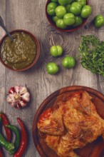 Baked tobacco chicken, served with tkemali sauce, on a wooden table, Georgian cuisine, rustic
