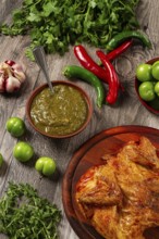 Baked tobacco chicken, served with tkemali sauce, on a wooden table, Georgian cuisine, rustic