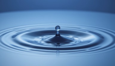 A captivating image of a water droplet creating ripples on a smooth, reflective blue surface,